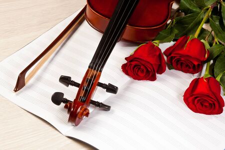 Red roses and a violin on the tableの写真素材