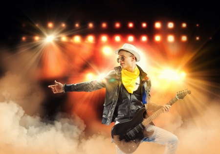 Young man, rock musician in jacket playing guitarの写真素材