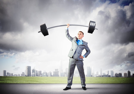 Image of strong businessman lifting barbell above head with one handの写真素材