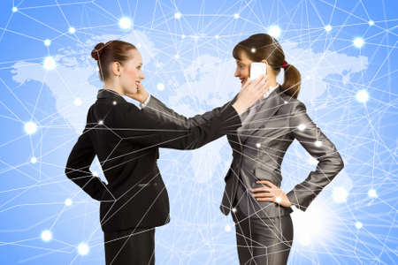 Two businesswomen talking on mobile phone  Cooperation conceptの写真素材