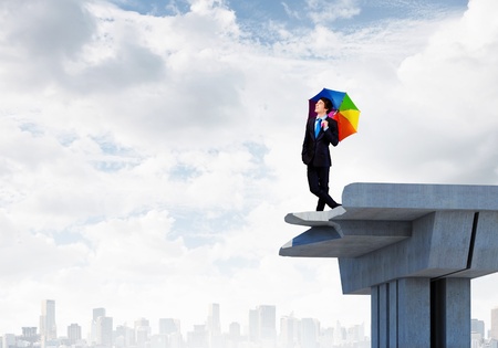 Image of businessman with umbrella standing at the edge of bridgeの写真素材