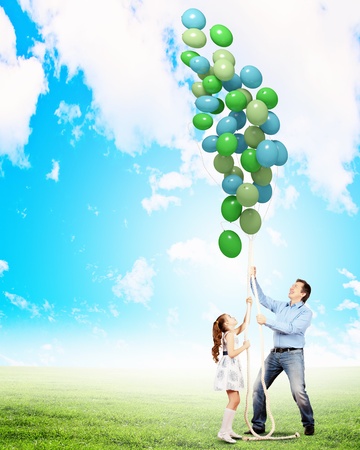 Image of father and daughter playing with bunch of colorful balloonsの写真素材