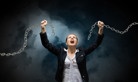 Image of businesswoman in anger breaking metal chainの写真素材