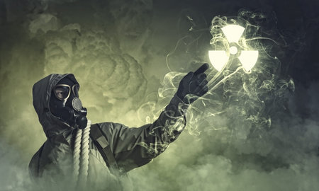 Man in respirator against nuclear background touching symbol  Pollution concept