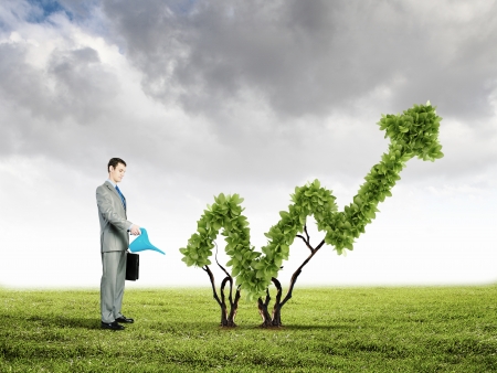 Image of businessman watering plant shaped like arrowの写真素材