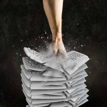 Image of human hand breaking pile of keyboards