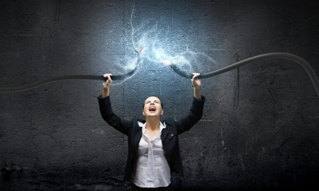 Image of businesswoman holding electrical cable above headの写真素材