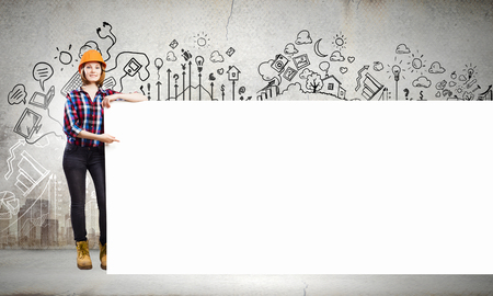 Image of young woman builder wearing helmet and holding blank bannerの写真素材