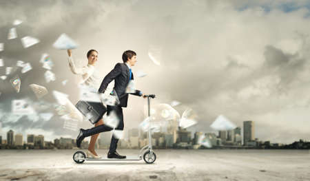 Image of young happy businesspeople riding scooterの写真素材