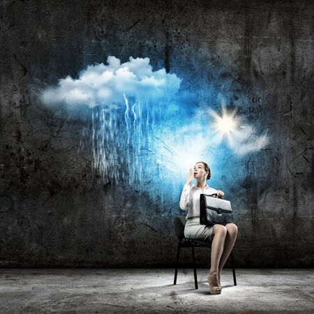 Image of young troubled businesswoman standing under rainの写真素材