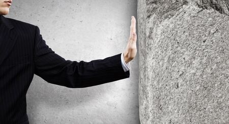 Businessman touching stone grey wall with palmの写真素材