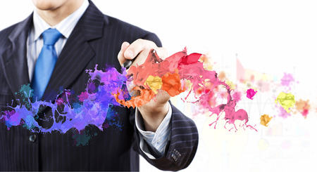 Businessman against white background drawing colorful splashes with markerの写真素材