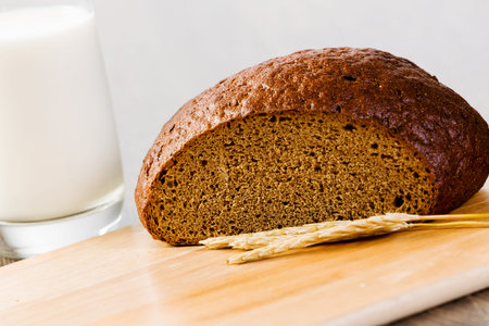 Fresh bread and glass of milk on table