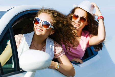 Young pretty women leaning out of car windowの写真素材