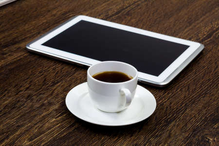 Tablet pc cup of coffee and notepad at tableの写真素材