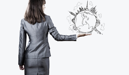Back view of businesswoman holding globe in palmの写真素材