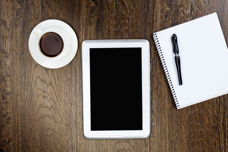 Tablet pc cup of coffee and notepad at table