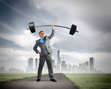 Image of strong businessman lifting barbell above head with one handの写真素材