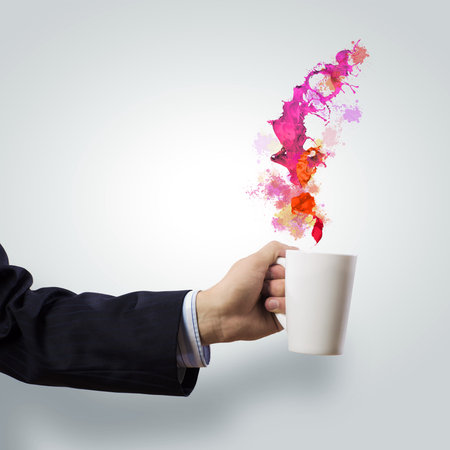 Businessman holding white cup with splashes in hand