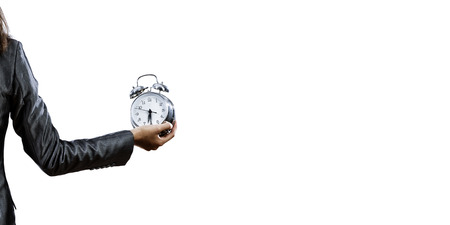 Back view of businesswoman holding alarm clock against white backgroundの写真素材