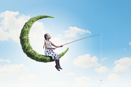 Little girl standing on moon and fishingの写真素材