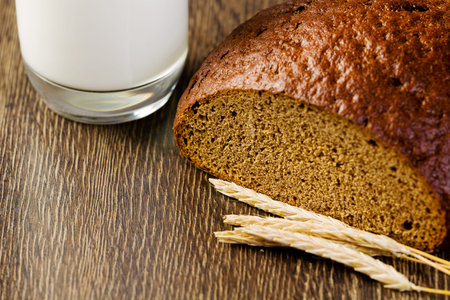 Fresh bread and glass of milk on table