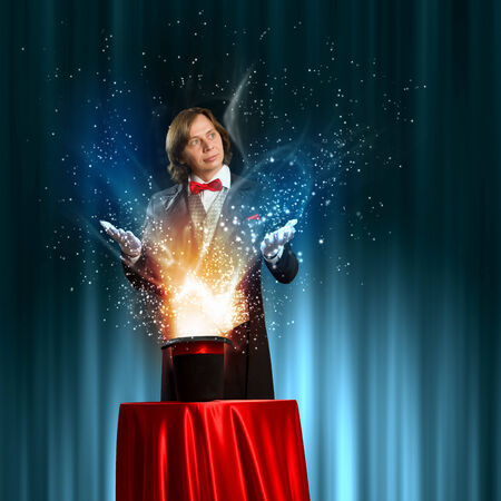 Image of magician holding hat with lights and fumes going outの写真素材