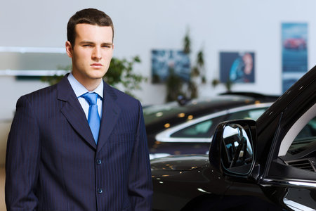 Image of handsome young businessman in suit standing near carの写真素材