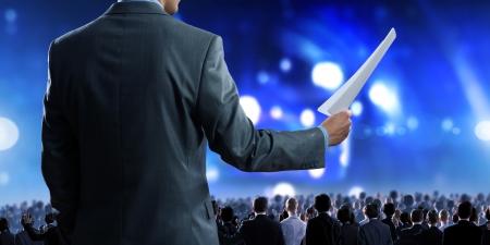 Back view of businessman speaker standing on podium with papers in handの写真素材