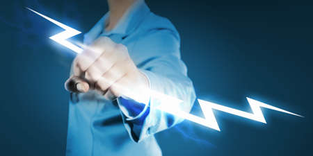 Image of powerful businesswoman holding lightning in fistの写真素材
