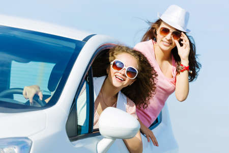Young pretty women leaning out of car windowの写真素材