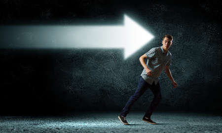 Young funny man ruining away from arrowsの写真素材