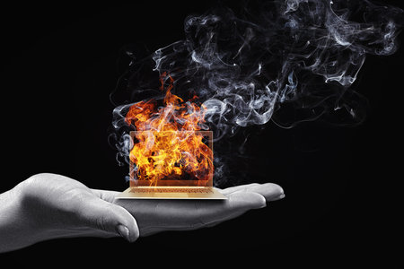 Human hand holding burning laptop on palmの写真素材