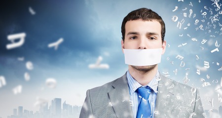 Young handsome businessman with adhesive tape on mouthの写真素材