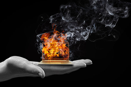 Human hand holding burning laptop on palmの写真素材