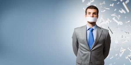 Young handsome businessman with adhesive tape on mouthの写真素材