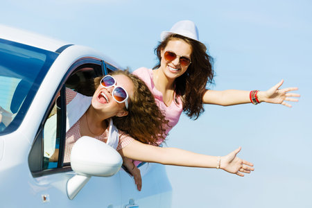 Young pretty women leaning out of car windowの写真素材