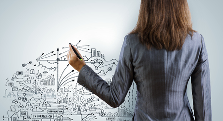 Back view of businesswoman drawing sketches with markerの写真素材