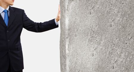 Businessman touching stone grey wall with palmの写真素材