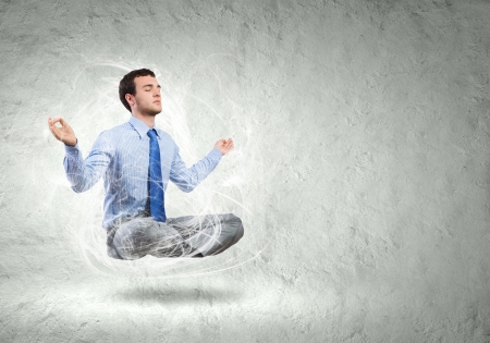 Young businessman sitting in lotus pose and meditatingの写真素材