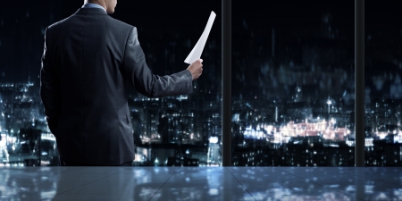 Businessman standing against office window reading documentsの写真素材