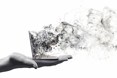 Human hand holding burning laptop on palmの写真素材