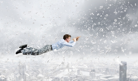 Young businessman flying in sky and playing fifeの写真素材