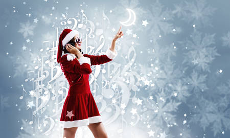 Young attractive Santa girl listening music in headphonesの写真素材