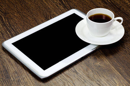 Tablet pc cup of coffee and notepad at tableの写真素材