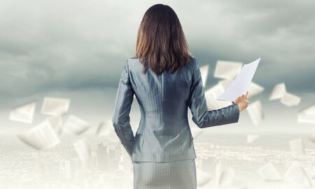 Back view of businesswoman holding papers in handsの写真素材