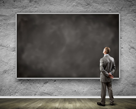 Rear view of businessman looking at chalkboardの写真素材