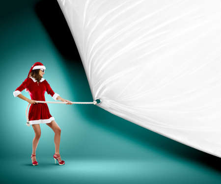 Young pretty woman in Santa suit pulling blank white banner  Place for textの写真素材