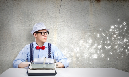 Young funny man in glasses writing on typewriterの写真素材