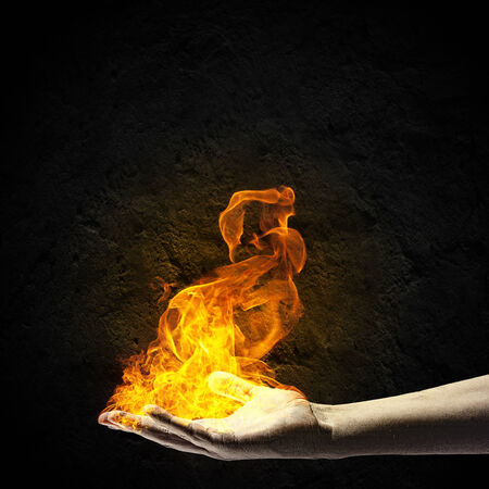 Close up of human hand holding fire flameの写真素材